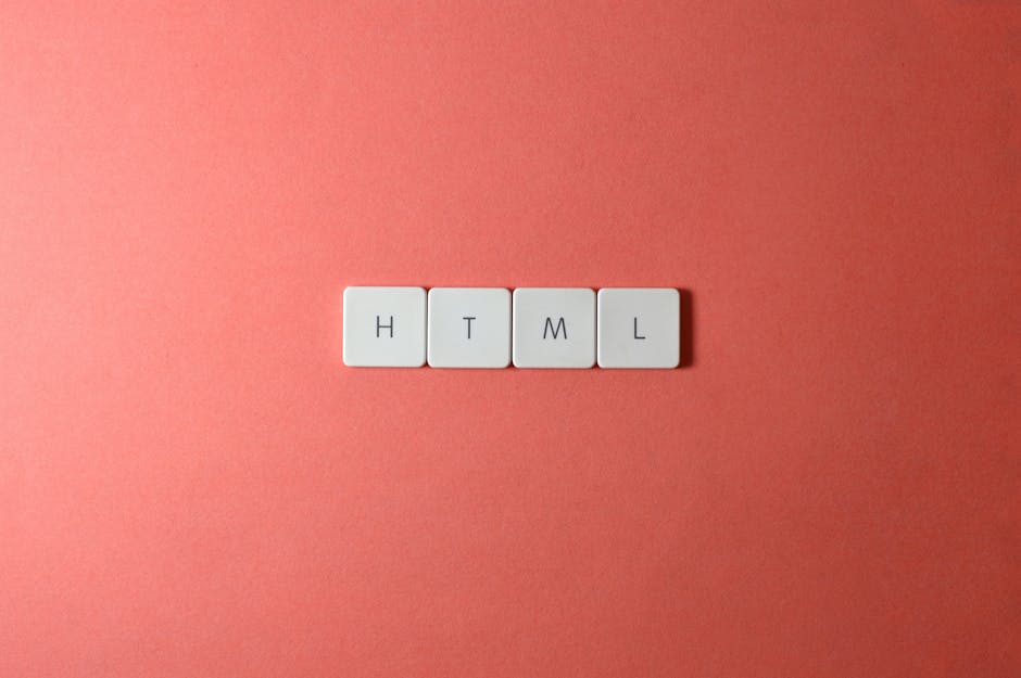 Close-up of four white keyboard keys spelling 'HTML' arranged on a pink surface, with natural light casting soft shadows around the keys, illustrating surface cleaning and organisation for domestic or